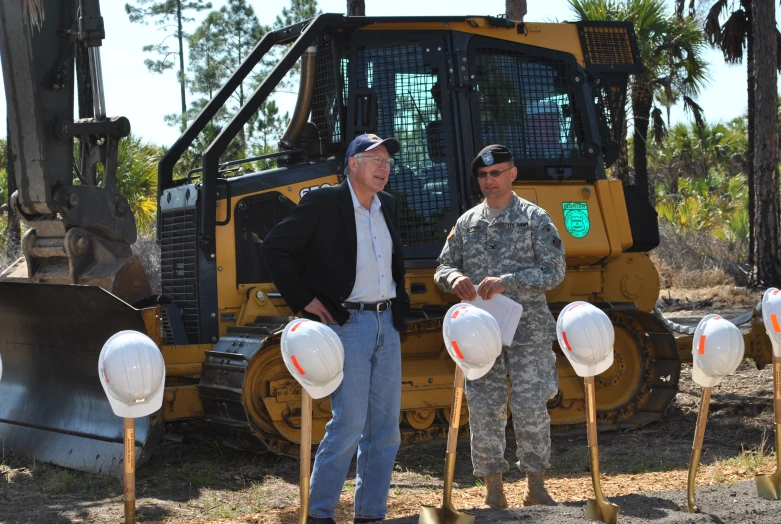 two men standing in front of a bulldozer