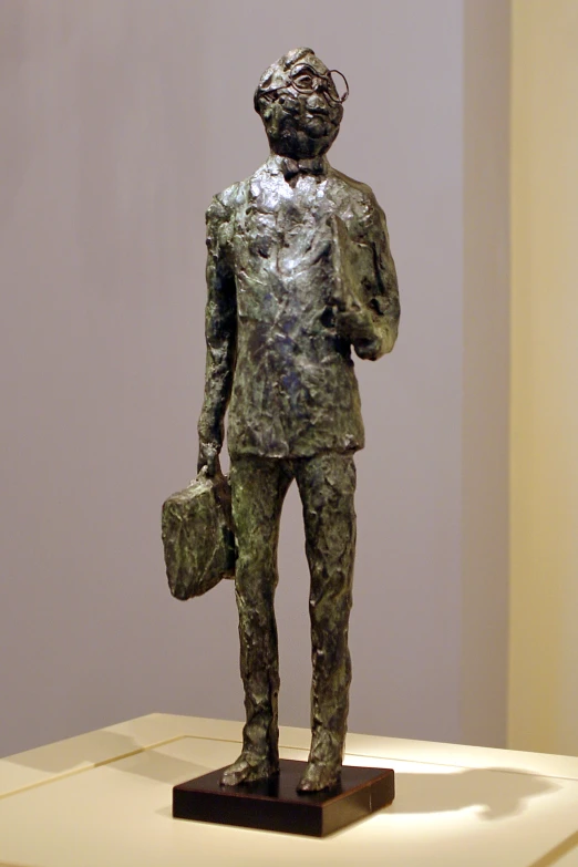 a bronze statue of a man with a bag, standing in a room