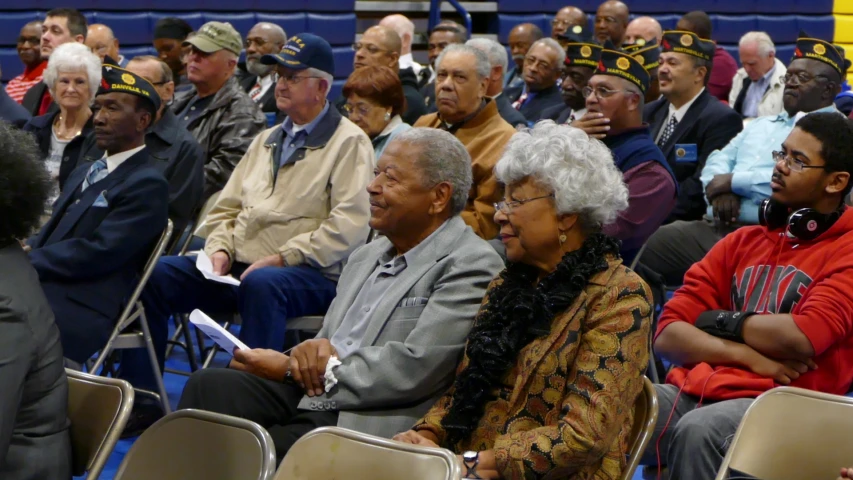 a group of people seated in a auditorium watching soing