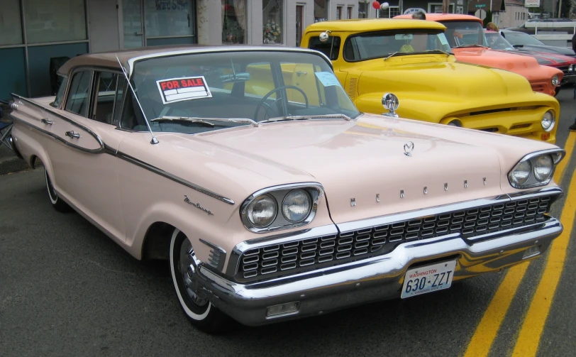 a beige and white car on street next to yellow cars