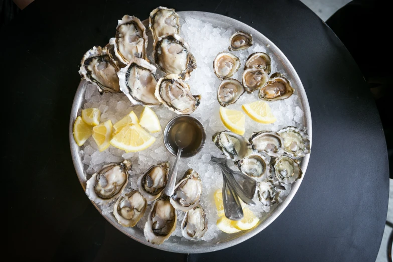 a plate with oysters, lemon wedges, and a spoon on it