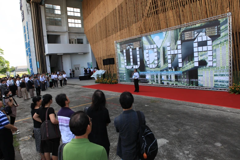 people gathered in front of an event showing a building