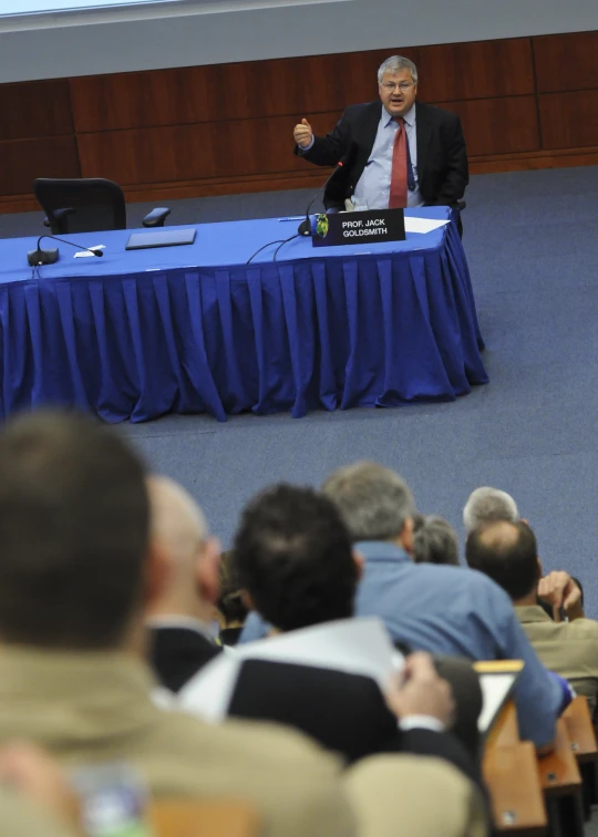 the man in a suit is giving a lecture