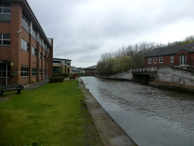 river flowing next to brick buildings with green grass