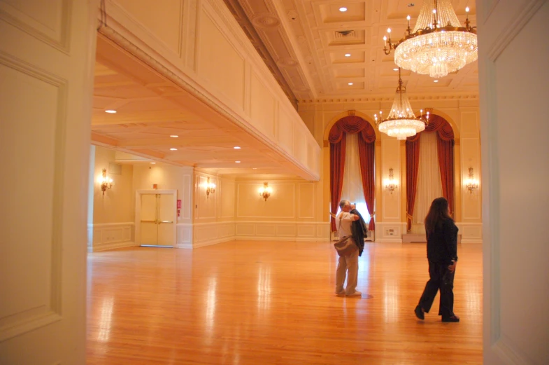 a po taken through a door shows two people walking in an ornate room