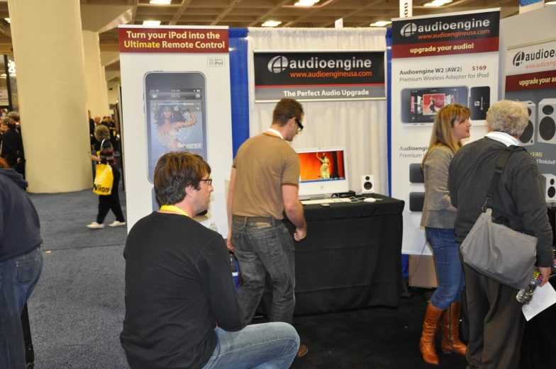 some people standing around looking at an exhibition screen