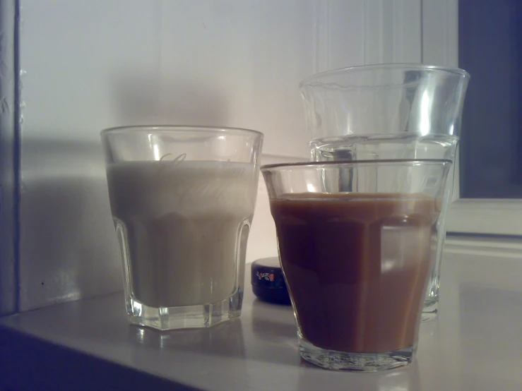 three different glasses of coffee on a counter