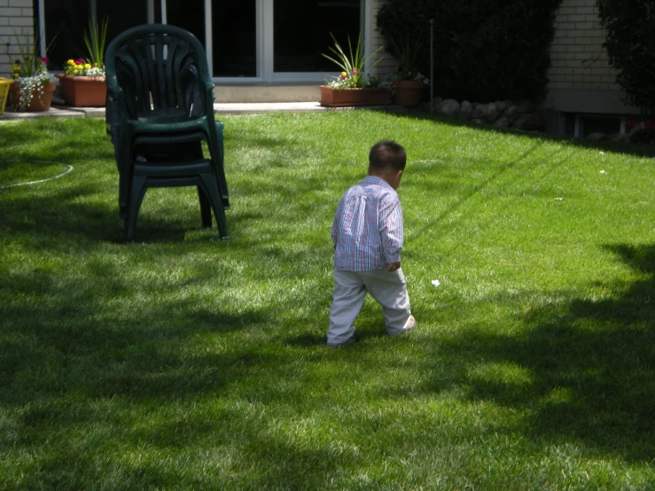 the baby boy is standing in a lawn
