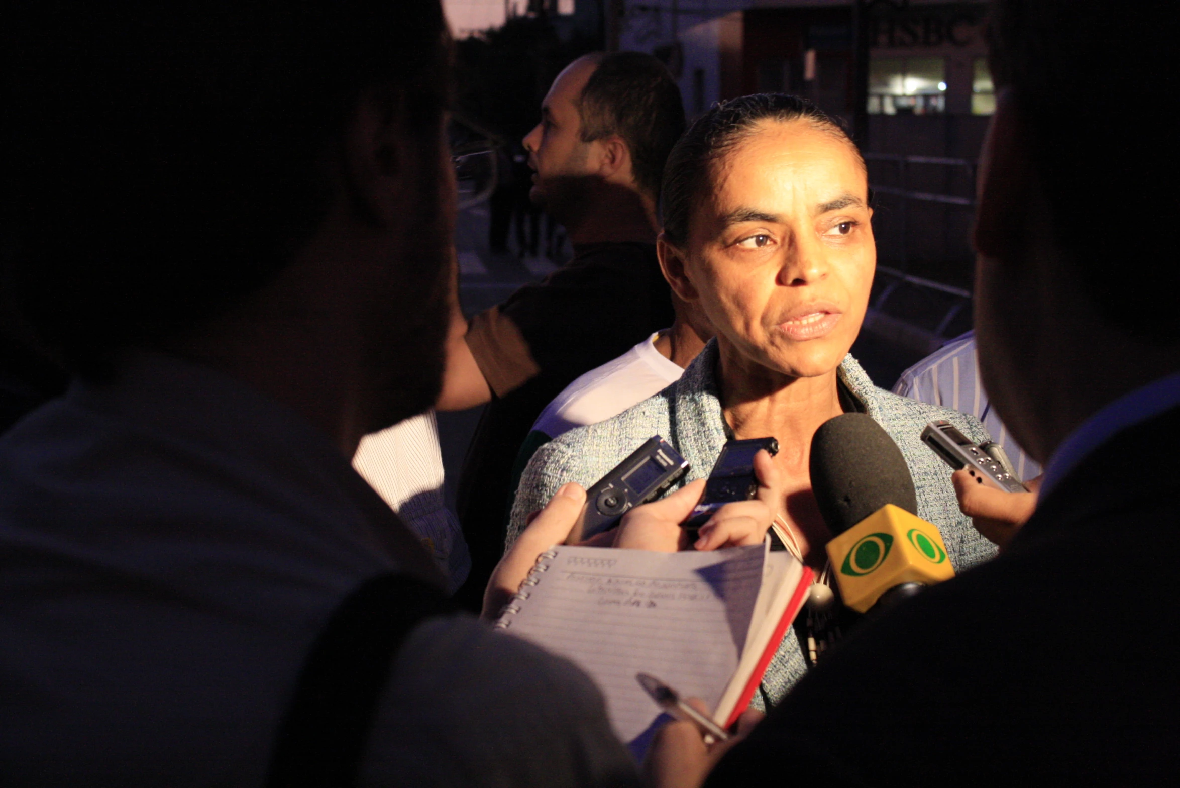 a man talking to reporters while holding microphones