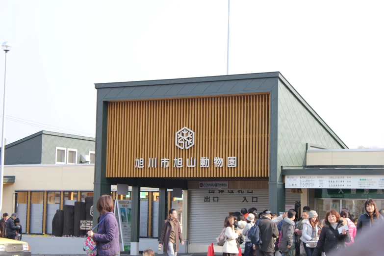 a group of people walk by the entrance of a shopping building