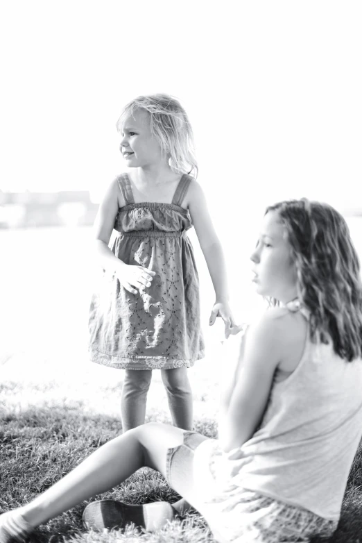 two little girls are sitting on the grass