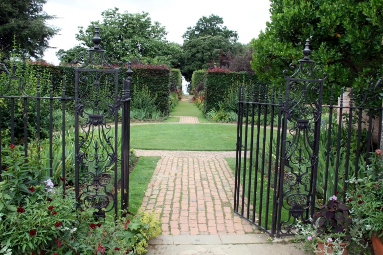 an iron gate leads through a flower garden