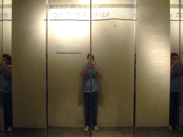 three people standing behind a mirror with one woman taking a selfie