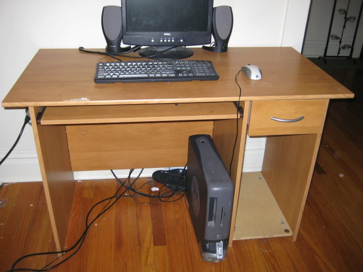 a computer on a wooden desk with another monitor and keyboard