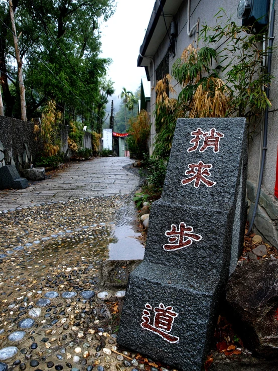the wall with stone, grass, and other signs has asian writing