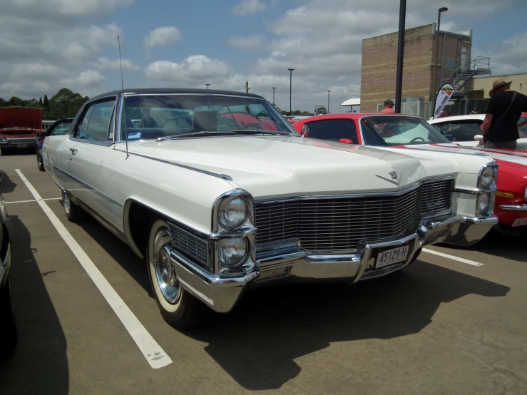 white classic car parked in lot with others nearby