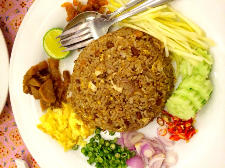 a rice with vegetables and a fork on a white plate