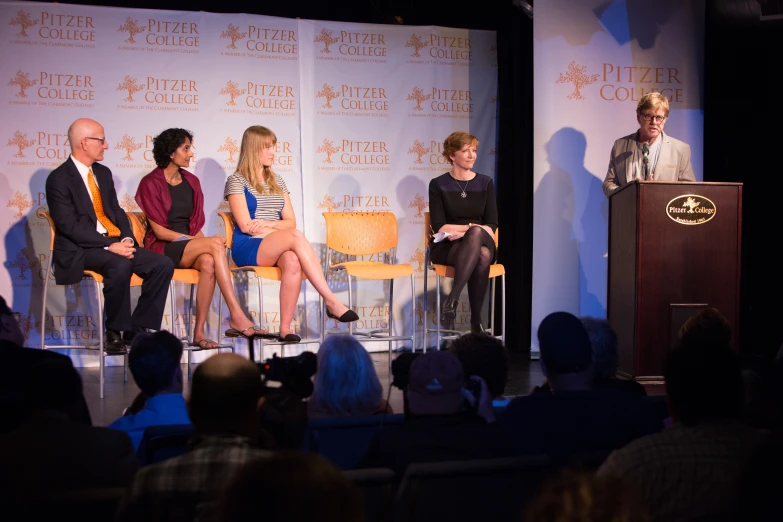 four people are sitting on stage having a panel