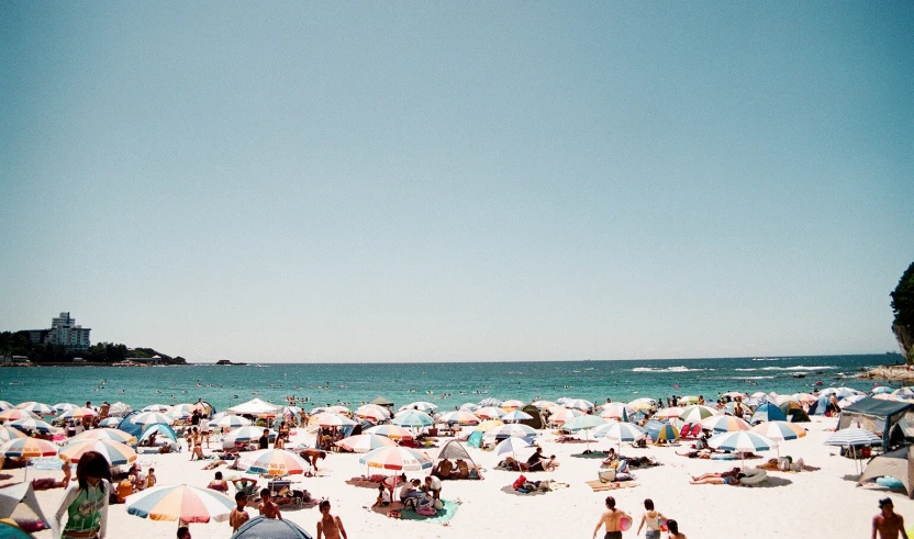 people are on a white beach and are under umbrellas