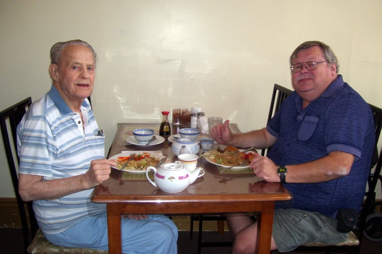 two men are seated at a small table and having coffee