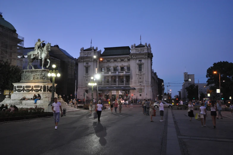 many people walk along the sidewalk outside in front of buildings