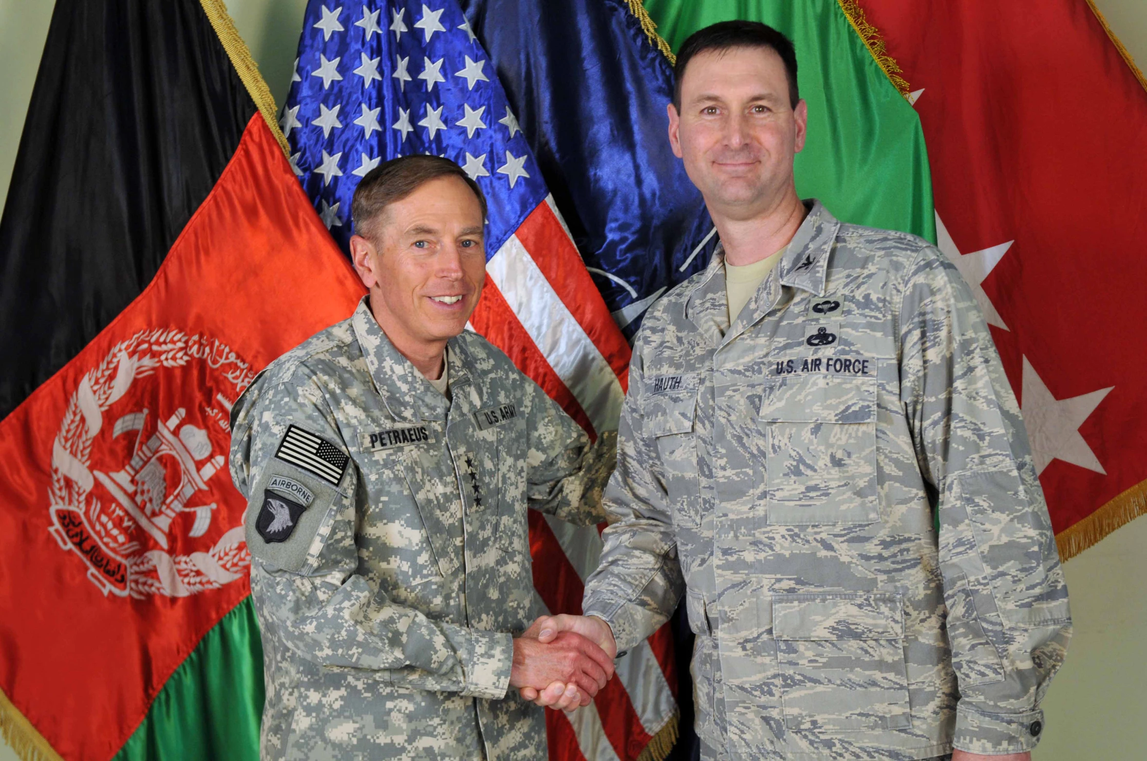 two men in uniforms standing in front of flags