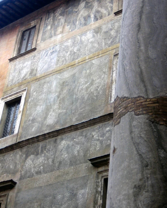 a wall with a clock and windows, in front of an old building