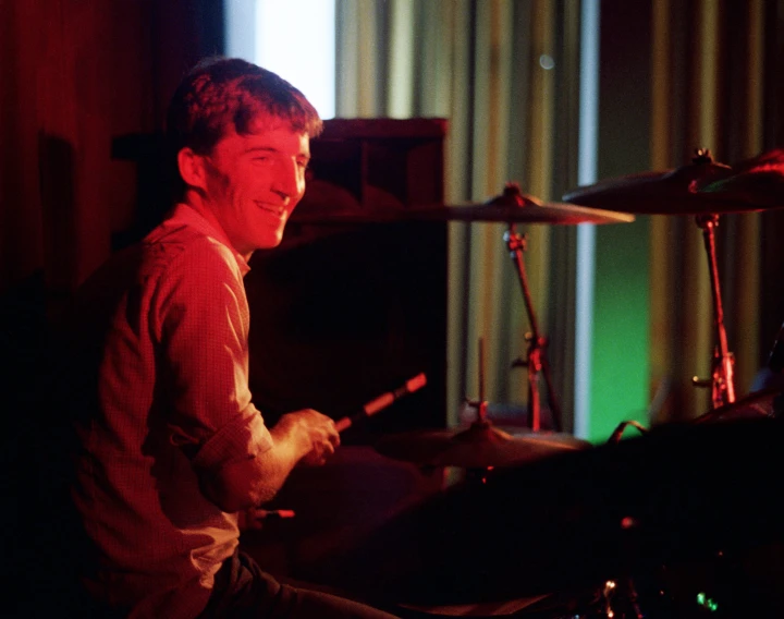 a man sits in front of his drums, drumming