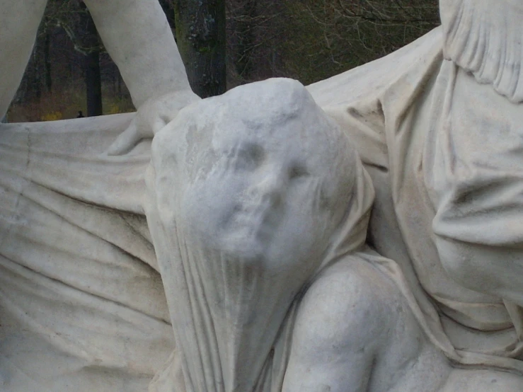 statues depicting the body and head of women, in front of trees