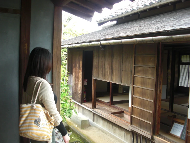 a woman standing next to a brown wooden building