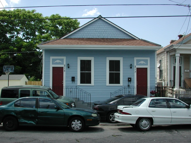 two cars parked outside of a small house