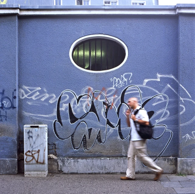 a man walks by a painted wall on a sidewalk