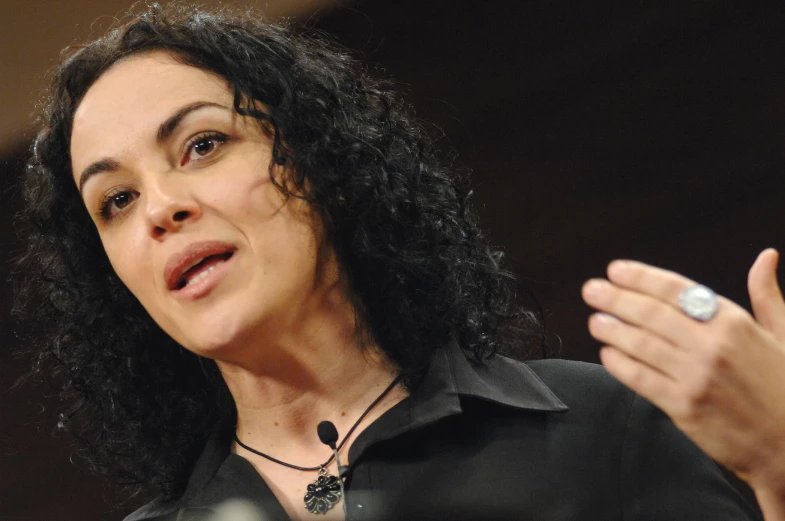 woman with curly hair gesturing in front of a microphone