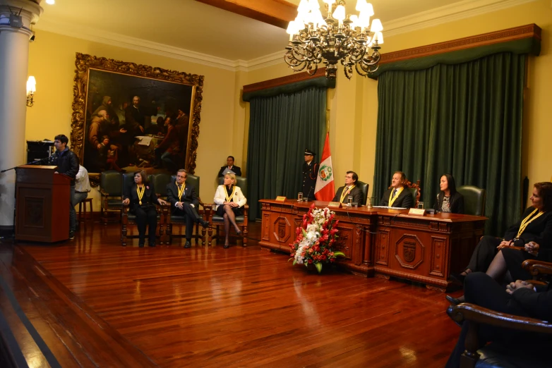 the man standing at a podium is speaking to people in suits and ties