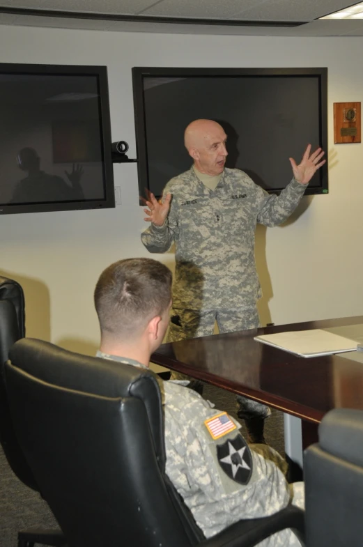 the man in the military uniform speaks to a group of people