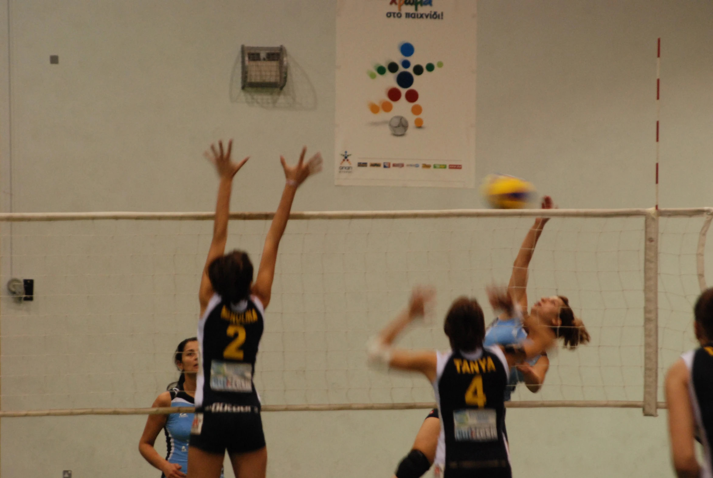 three girls are playing volleyball, one is hitting the ball