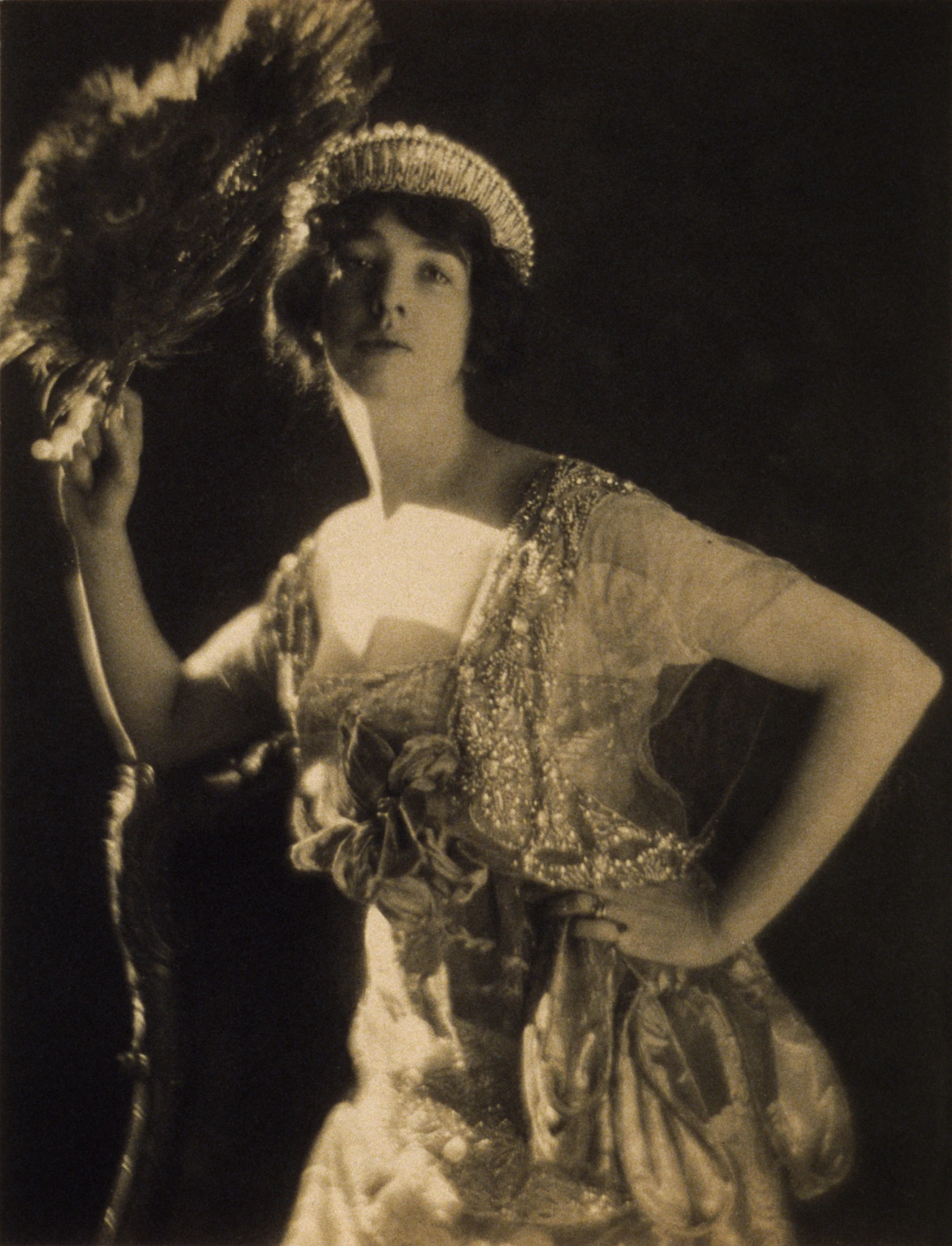 woman wearing costume holding a feather or fan with one hand