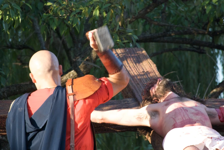 two men with paint on their bodies hanging from a ladder