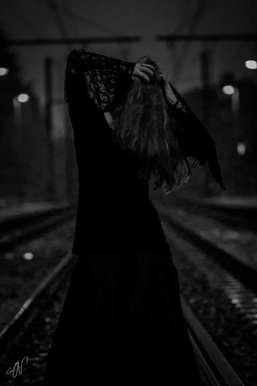 a black and white image of a woman walking down the tracks