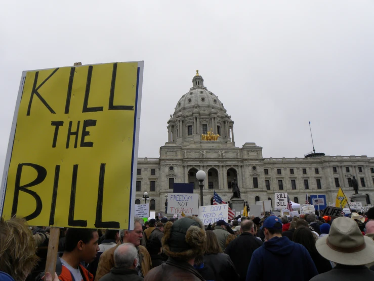 people are protesting on a gray day in front of an old building