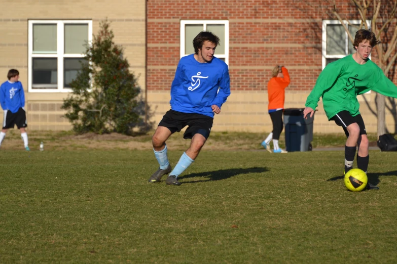 a boy in a green jersey running after a soccer ball