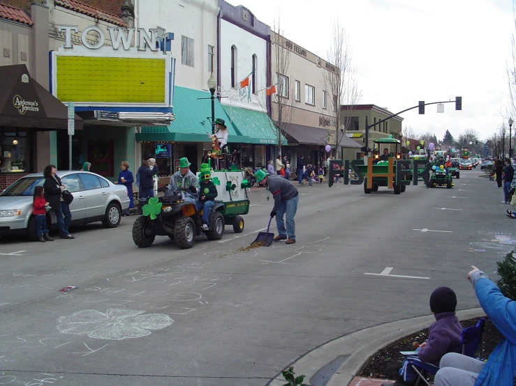 some people cars and some green vehicles in the street