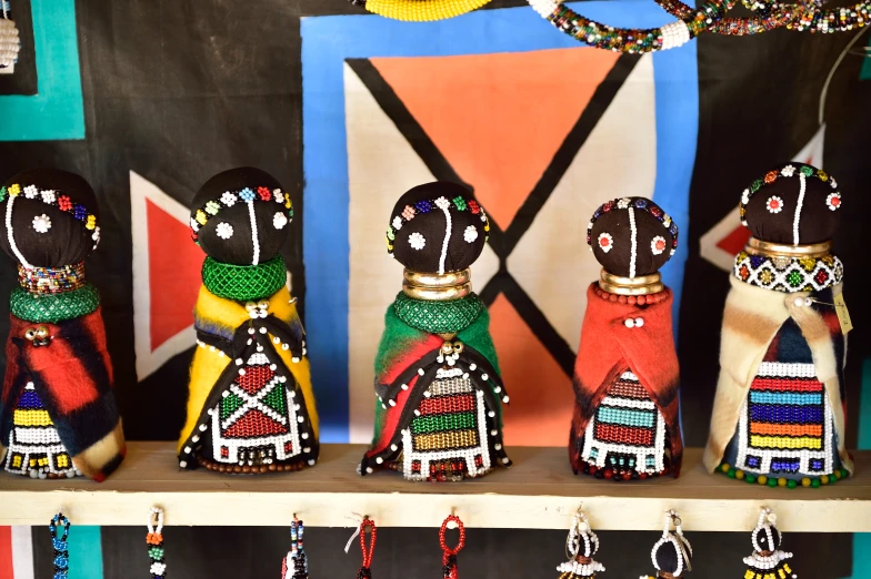 a wooden shelf displaying small african painted dolls