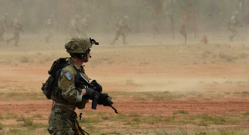 the soldiers is carrying their weapon while other military men are behind them