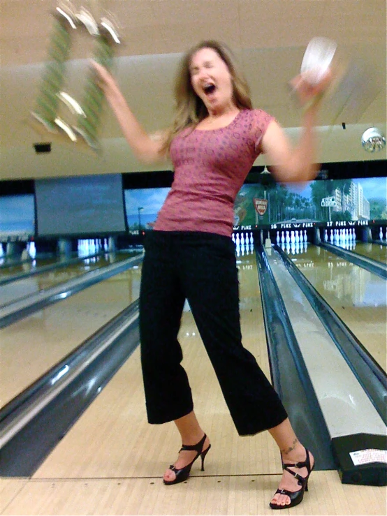 a woman is laughing and bowling in an indoor bowling hall