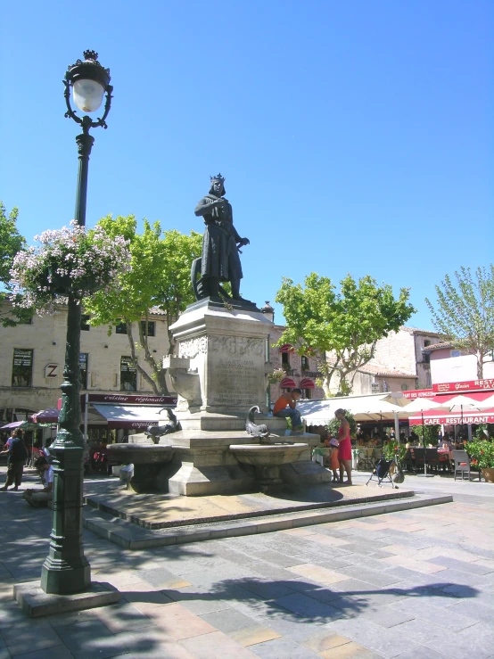 a statue with a man standing on it in the middle of a square