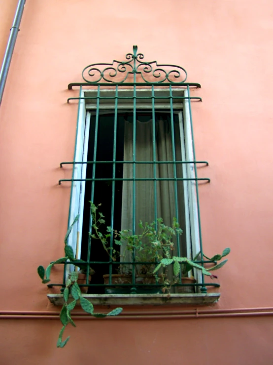 a window on a wall with metal bars and wire