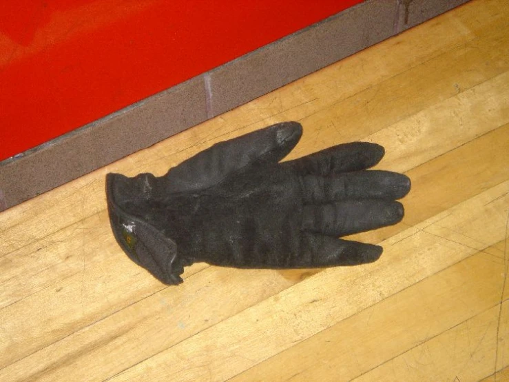black gloves on a wooden floor near a brick wall