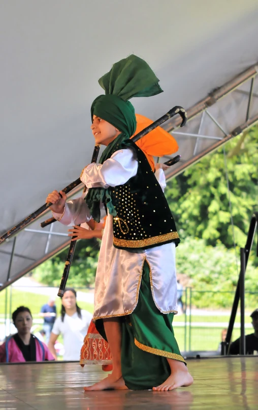 an indian dancer performing with sticks at a children's festival