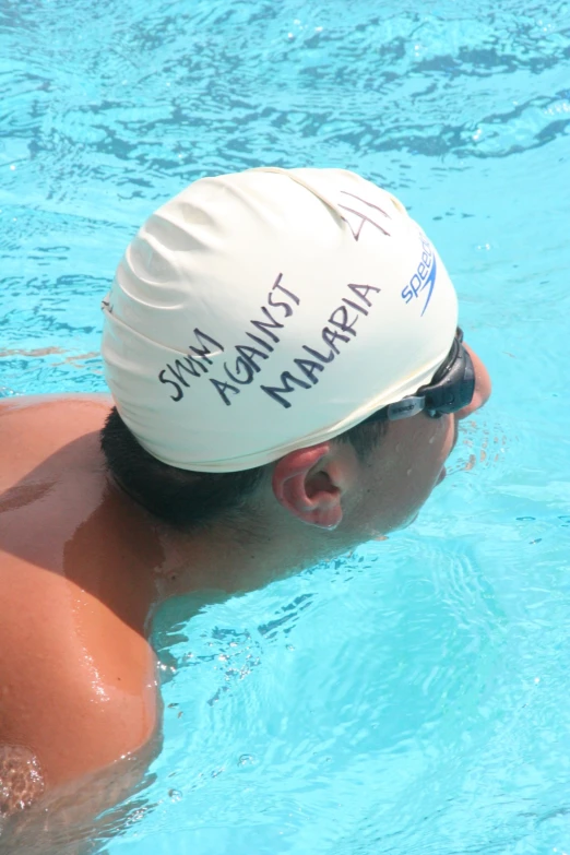 a man is swimming in a pool with an empty hat